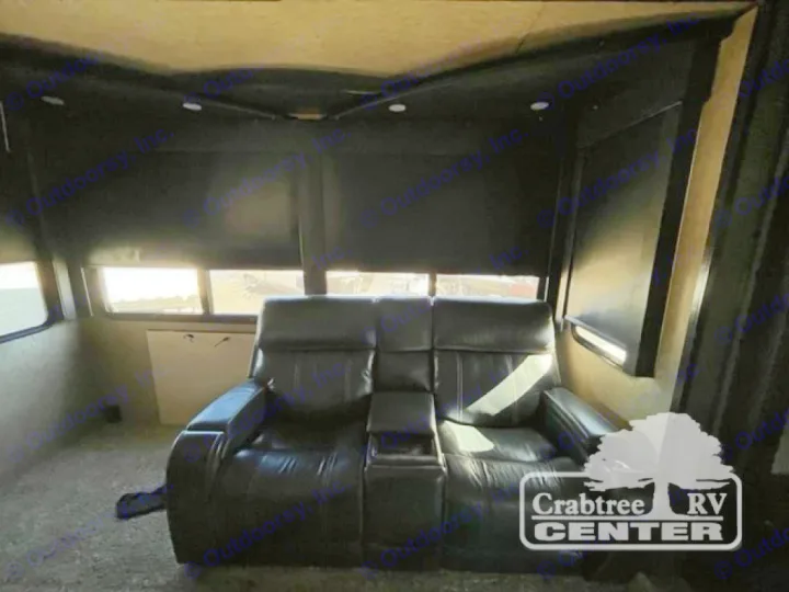 Cozy RV rental living area featuring dark leather recliners, bright windows with blinds, and dim interior lighting.. Grand Design Momentum 2015