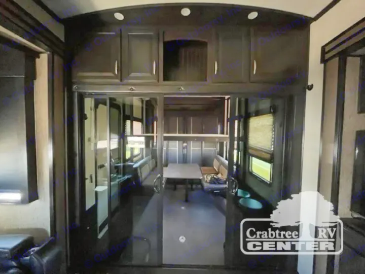 RV rental interior: Dark wood cabinets, glass sliding doors reveal a toy hauler's dining/garage area.. Grand Design Momentum 2015