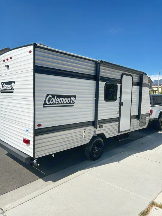 A modern Coleman travel trailer, ideal for an RV rental, is hitched to a truck on a clear, sunny day.. Coleman Lantern 17B 2025