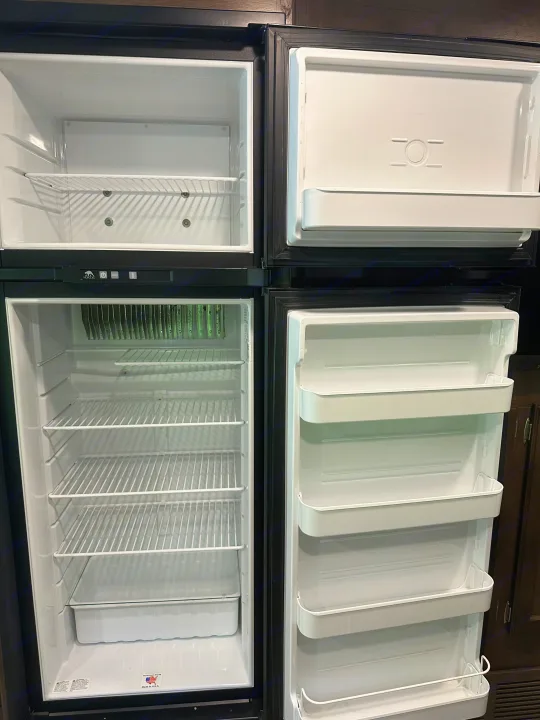 Open RV rental refrigerator & freezer, empty with wire shelves and door bins, ready for your travel food.. Jayco Redhawk 2018