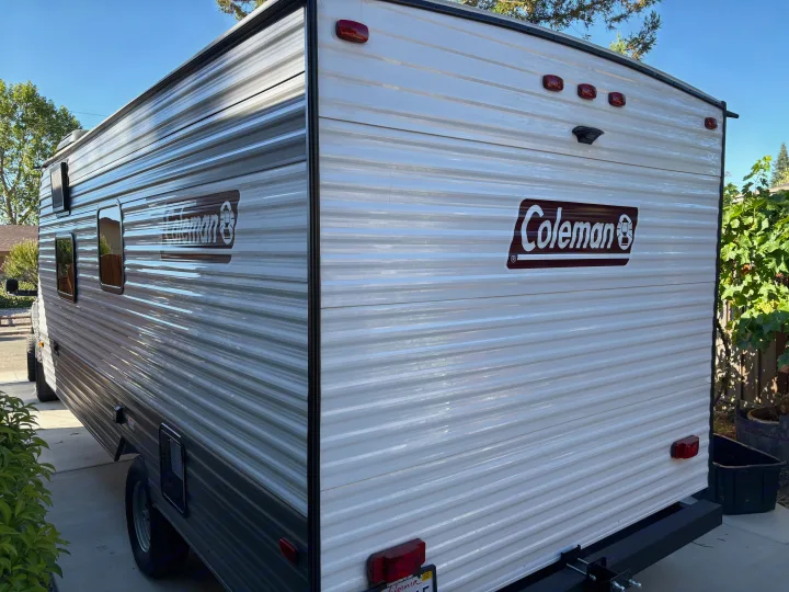 Explore with this clean Coleman RV rental! Features a rear and side view of the white and grey travel trailer.. Dutchmen Kodiak Cub 2024