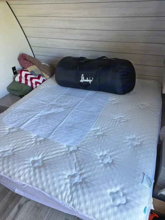 Setup for an RV rental: a plush mattress with a protector, folded blankets, and a Slumberjack bag in the bedroom.. Dutchmen Kodiak Cub 2024