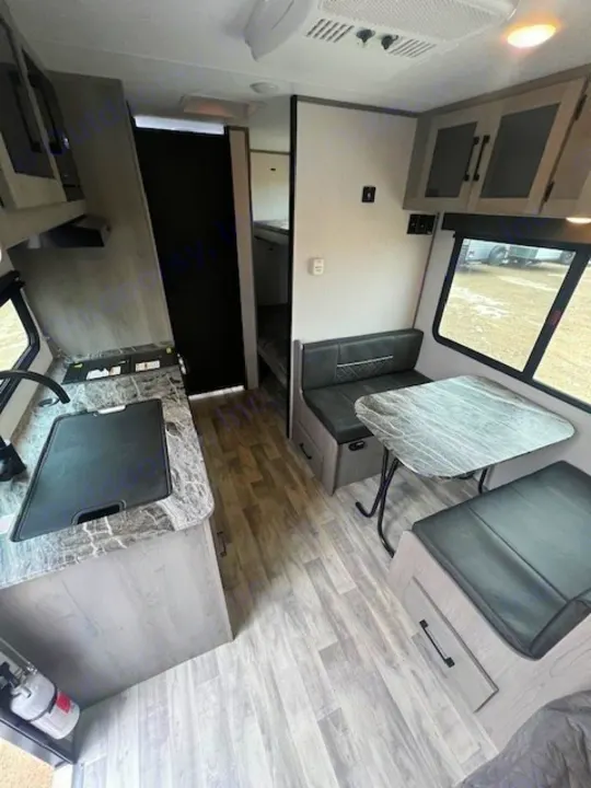 Explore this RV rental's interior, showcasing a modern kitchen, dinette, and glimpses of the bunk area, all on stylish wood-look flooring.. Dutchmen Kodiak Cub 2022