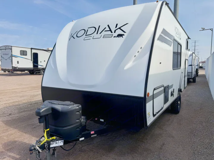 White Kodiak Cub travel trailer in an outdoor lot, ready for your next RV rental adventure. Ideal for camping.. Dutchmen Kodiak Cub 2022