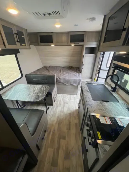 RV rental interior features a bed, dinette, and kitchen with light wood finishes. A compact space for your next adventure.. Dutchmen Kodiak Cub 2022