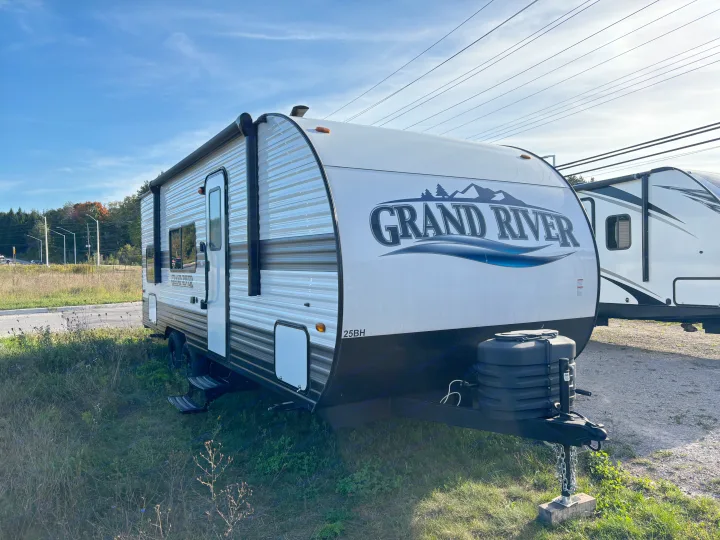 Explore this Grand River 25BH travel trailer, ready for your next adventure as an rv rental, parked outdoors under power lines.. Forest River grand river 2024