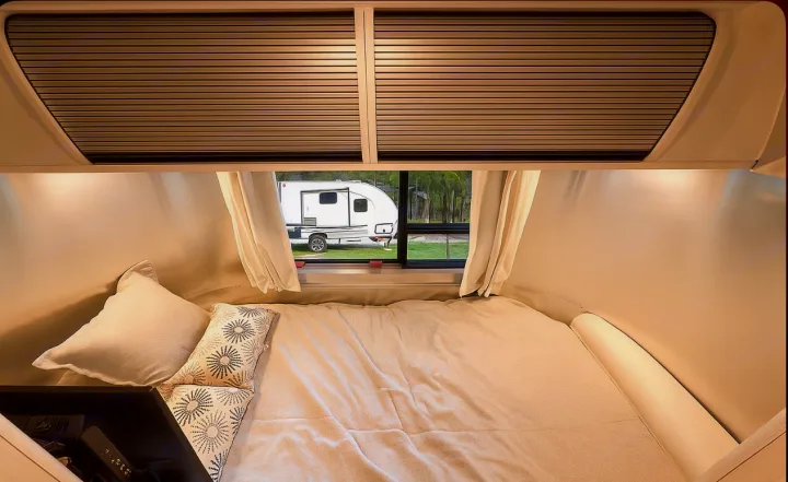 Cozy RV rental bedroom featuring a comfortable bed and a window view of another camper outside.. Airstream Bambi 2024
