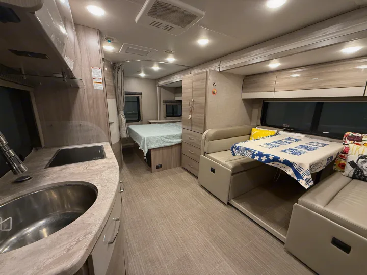 This RV rental's inviting interior showcases a compact kitchen, comfortable dining area, and a cozy bedroom.. Thor Tiburon SV 2023