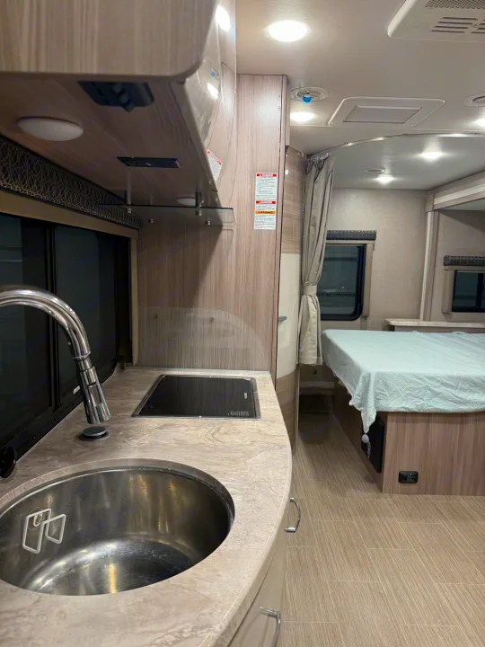 This RV rental features a modern galley kitchen with a stainless steel sink, electric stovetop, and a comfortable sleeping area.. Thor Tiburon SV 2023