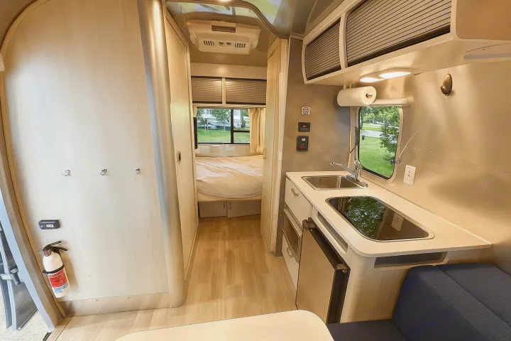 Explore this bright rv rental interior, highlighting its functional kitchen, cozy bedroom, and modern design with essential amenities.. Airstream Bambi 2024