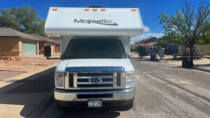 Front view of a white Ford Majestic RV rental, parked on a residential street under a blue sky, ready for travel.. Thor Majestic 2019