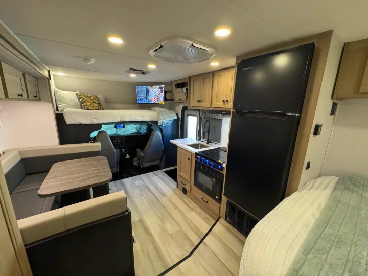 This inviting rv rental features a full kitchen, dining area, and a bunk bed above the cab in a bright, modern interior.. Forest River Sunseeker 2026