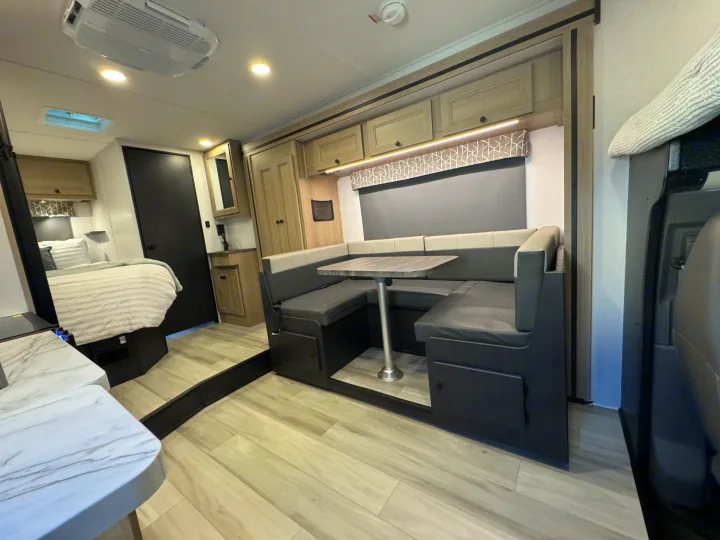 Modern RV rental interior: U-shaped dinette, bed, light flooring. Perfect for your next adventure.. Forest River Sunseeker 2026