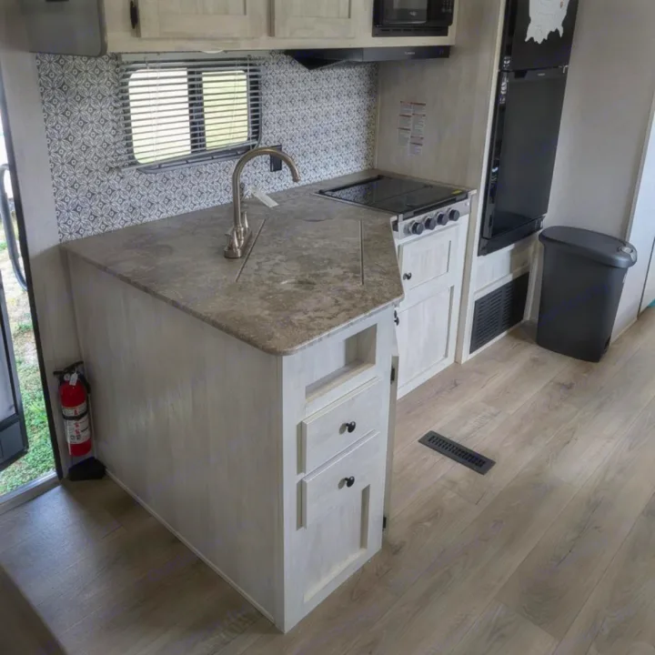 This modern RV rental kitchen features a sink, stove, fridge, and stylish patterned backsplash. Ready for adventure!. Coachmen I-5 Edition 530QB 2024