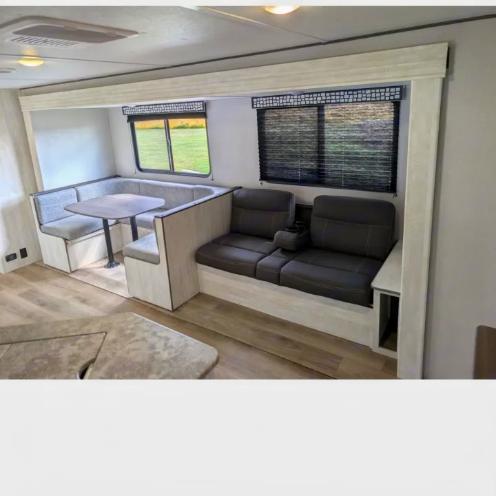 Modern RV rental interior featuring a cozy dinette with a table and a comfy dual recliner sofa with cup holders.. Coachmen I-5 Edition 530QB 2024