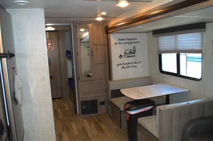 Inside this RV rental: a comfortable dinette with a witty camping quote wall, plus a peek at bunk beds in the hallway.. Gulf Stream Kingsport 2021