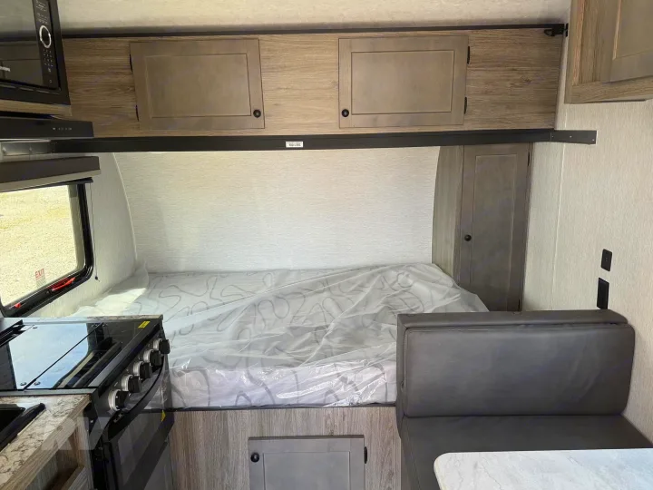 Inside an RV rental, featuring a bed, kitchen area with a stove, a dinette, and overhead storage cabinets.. Sunlite 16BH 2025