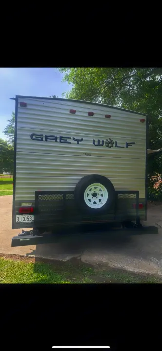 Back of a Grey Wolf travel trailer, seen from the rear with a spare tire and cargo rack. Perfect for your next rv rental.. Forest River Cherokee Grey Wolf 2014