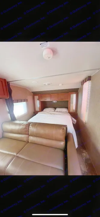 Cozy RV rental bedroom & living area: a comfortable bed, brown sofa, and ample storage for your journey.. Forest River Cherokee Grey Wolf 2014