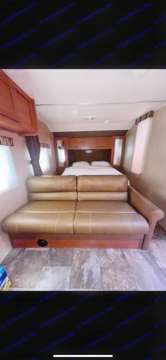 RV rental interior featuring a brown couch, bed in the rear, and bright windows, offering a cozy living space.. Forest River Cherokee Grey Wolf 2014