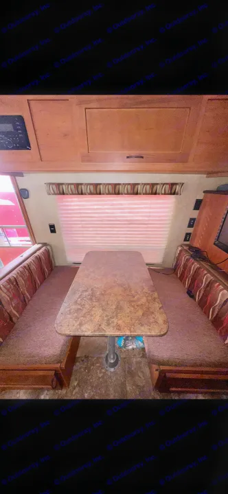 RV rental interior: dinette with patterned cushions, a brown speckled table, and wooden overhead cabinets.. Forest River Cherokee Grey Wolf 2014