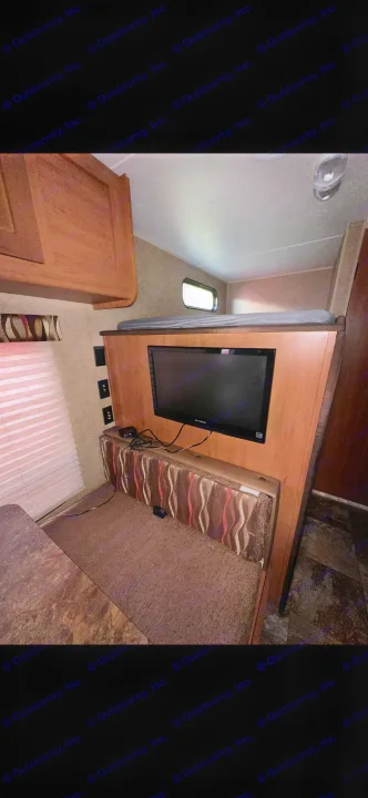 RV rental interior features a dinette with mounted TV, a bunk bed above, and ample storage cabinetry.. Forest River Cherokee Grey Wolf 2014