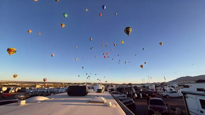 Dozens of colorful hot air balloons soar above a massive RV park. Imagine this breathtaking festival view from your rv rental!. Coachmen Freelander 2023