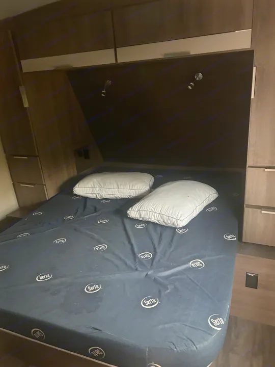 rv rental bedroom with a Serta mattress, two pillows, and dark wood cabinetry for a compact, comfortable camper interior.. Grand Design Imagine 2021