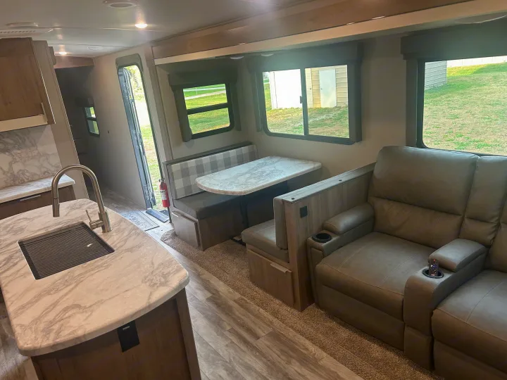 Inside a stylish RV rental: kitchen with sink, cozy dinette, and plush recliners. Ready for your adventure.. Grand Design Imagine 2021
