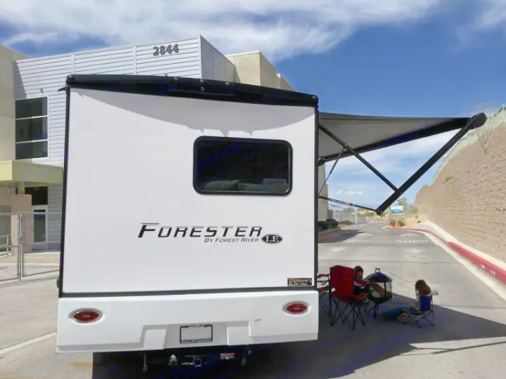 An RV rental, a Forester by Forest River, has its awning extended with people relaxing under it, enjoying outdoor time.. Forest River Forester 2026