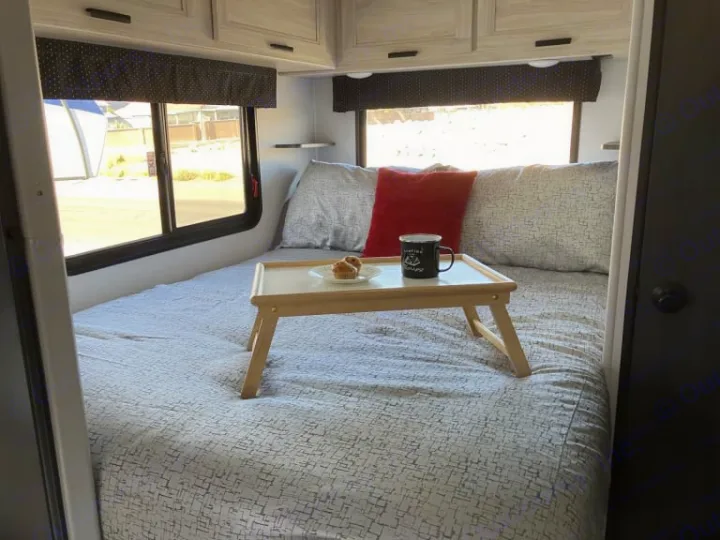 Inside a comfy RV rental: a bed with a breakfast tray, mug, and muffins, ready for a cozy start to your travels.. Forest River Forester 2026