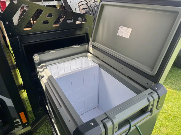 Open, olive-green Truma portable fridge/cooler, installed in an outdoor RV rental setup.. Mission Overland Summit 2024
