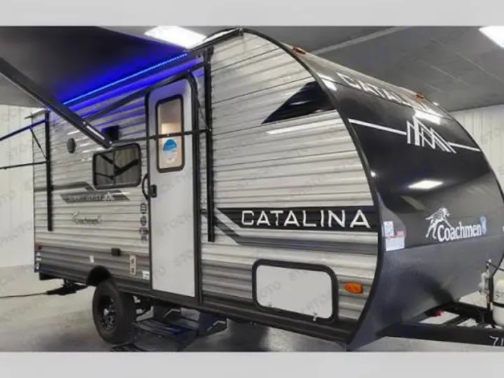 This sleek Coachmen Catalina travel trailer, with its awning extended and blue lights on, is ideal for an rv rental adventure.. Coachmen 184BH 2025