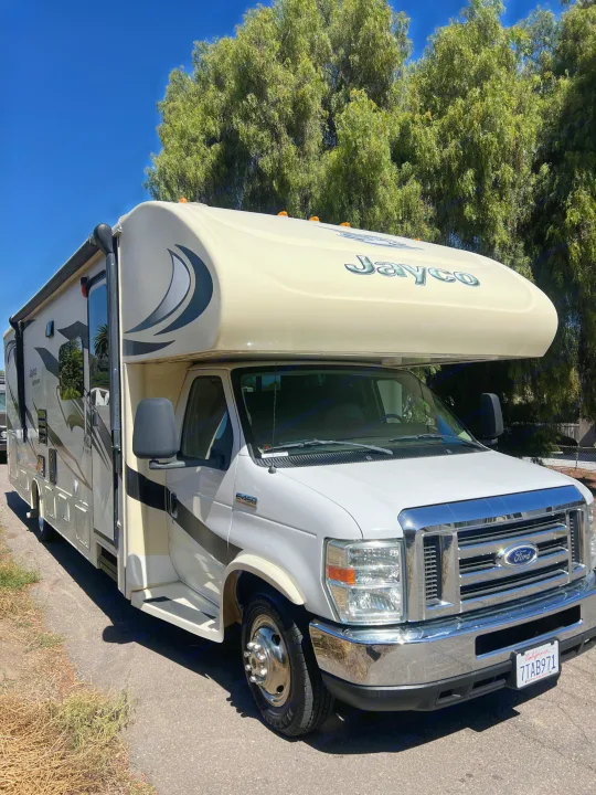 A clean Class C Jayco Ford E-450 rv rental is parked outdoors under a blue sky, ideal for your next road trip adventure.. Jayco Greyhawk 2016