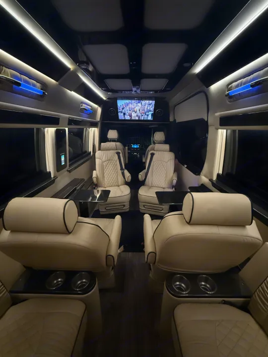 Luxurious RV rental interior with cream-colored, quilted leather seats, an entertainment screen, and ambient lighting.. Ultimate Toys Ultimate Coach 2023