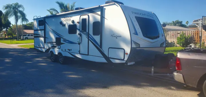 Ready for adventure! This Freedom Express RV rental travel trailer is hooked to a truck, perfect for outdoor trips.. Coachmen 292BHDS 2021