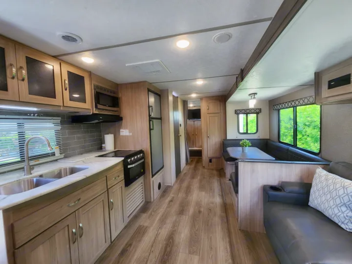 View of a clean, modern RV rental interior with a fully equipped kitchen, dinette, and cozy living space.. Coachmen 292BHDS 2021
