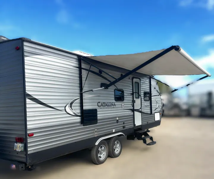 This grey Catalina travel trailer rv rental shows its extended awning, entry steps, and dual wheels.. Coachmen Catalina 2017