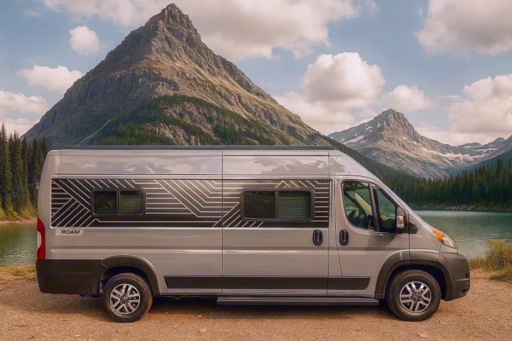 Gray ROAM rv rental camper van by a serene mountain lake, surrounded by majestic peaks and evergreen trees.. Winnebago Roam 2024
