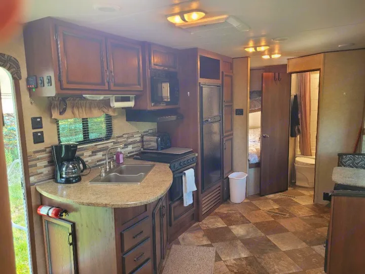 RV rental interior with a full kitchen, sleeping area with bunk beds, and compact bathroom.. Crossroads RV Zinger 2015
