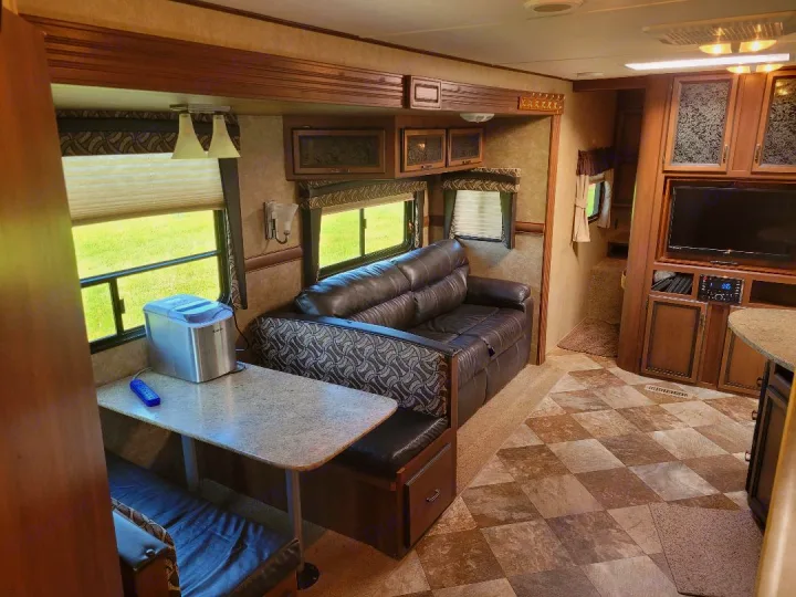 This inviting RV rental interior showcases a dinette, couch, entertainment center, and a handy ice maker. Ready for your adventure!. Crossroads RV Zinger 2015