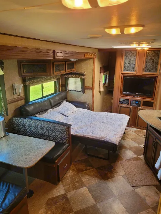 Cozy RV rental interior featuring a dinette, sofa bed, kitchen counter, and entertainment center. Ideal living space for travel.. Crossroads RV Zinger 2015
