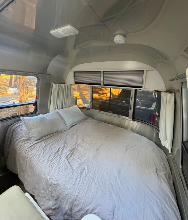 Airstream RV rental bedroom with soft grey bedding and nature views outside. Ideal for travel and relaxation.. Airstream Sport 2018