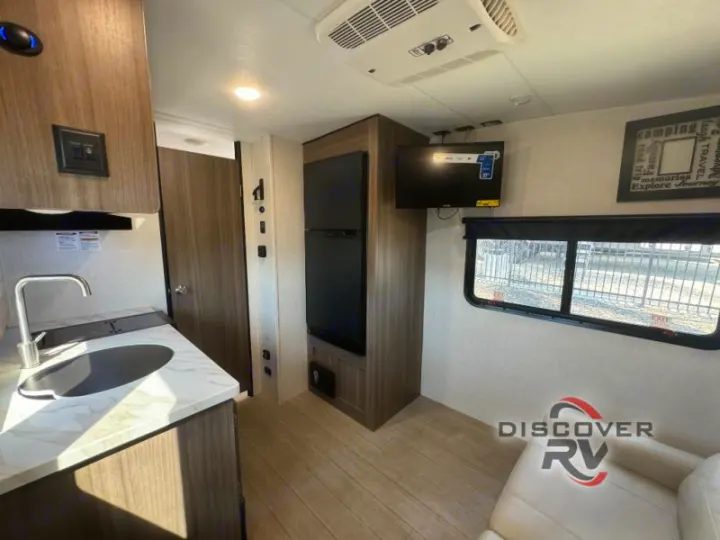 Bright rv rental interior featuring a modern kitchenette, full fridge, mounted TV, and comfy seating.. Sonic Lite 2021