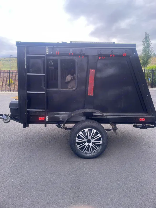 Explore with this compact black adventure trailer, perfect for RV rental. Features a window, wheel, and reflective accents.. Custom Squaredrop Trailer 2020