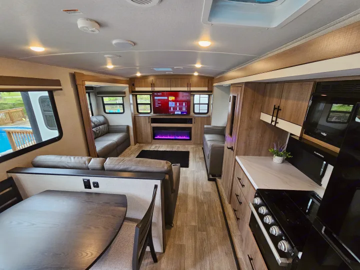 Modern RV rental interior featuring a living area with a fireplace, kitchen, and dining table.. Grand Design Imagine 2024