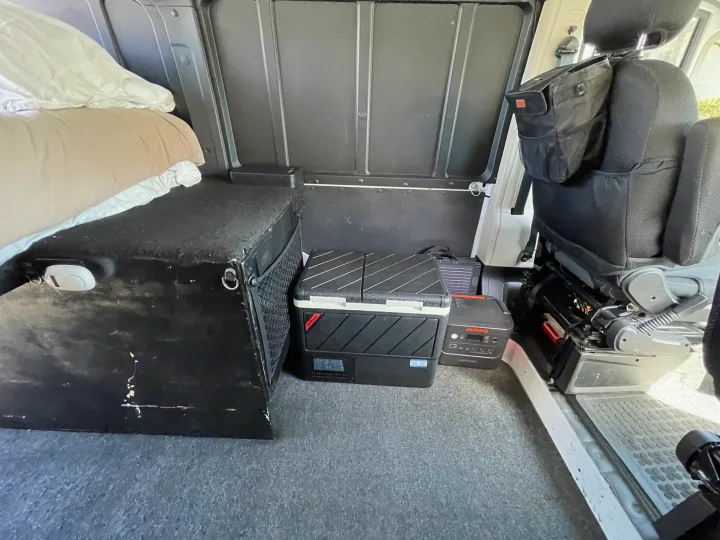 This RV rental interior offers a bed, portable fridge, Jackery power, and seat storage for comfortable travel.. Ram Promaster 2022