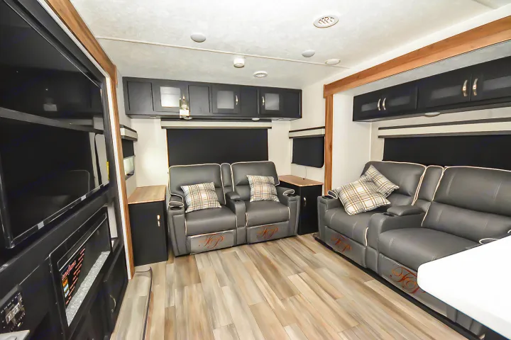 Spacious RV rental living room with comfortable recliners, modern black cabinets, and a large TV for entertainment.. Coachmen Coachmen Freedom Express Liberty Edition (324RLDSLE) 2022