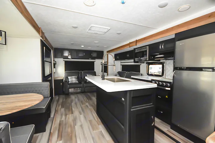 RV rental interior: modern kitchen island, stainless fridge, microwave, dinette, and living area with recliners/sofa.. Coachmen Coachmen Freedom Express Liberty Edition (324RLDSLE) 2022
