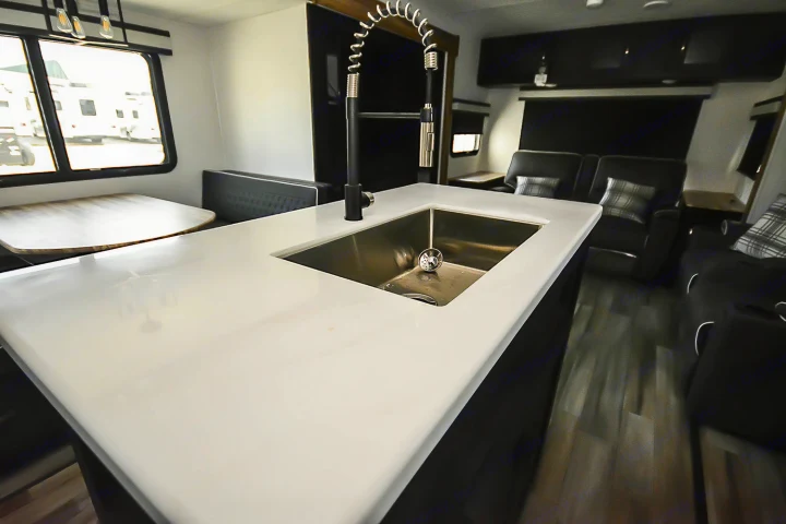 Bright RV rental interior: a modern kitchen island with sink, dinette, and comfy living area with recliners.. Coachmen Coachmen Freedom Express Liberty Edition (324RLDSLE) 2022